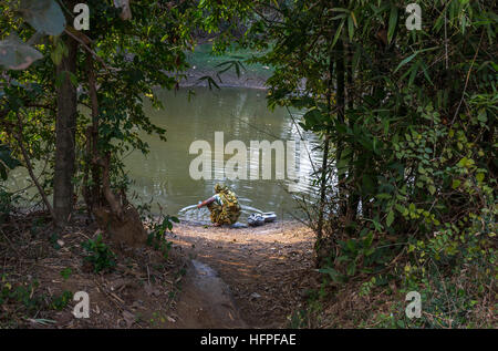 Rural Indian woman washes her utensils in a village pond at Bankura, West Bengal, India. Stock Photo