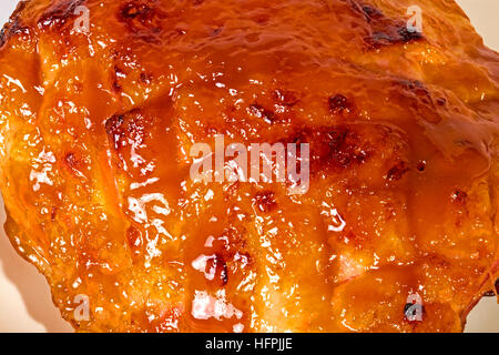Studio shot close up of baked gammon covered with honey based glaze on white plate Stock Photo