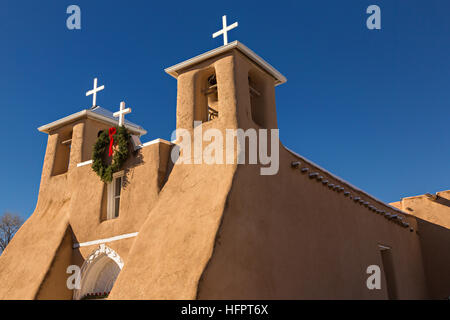 Historic San Francisco de Asis Mission Church decorated with a Christmas wreath in Ranchos de Taos Plaza, Taos, New Mexico. The adobe church built in 1772 and made famous in paintings by artist Georgia O'Keeffe. Stock Photo