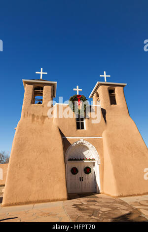 Historic San Francisco de Asis Mission Church decorated with a Christmas wreath in Ranchos de Taos Plaza, Taos, New Mexico. The adobe church built in 1772 and made famous in paintings by artist Georgia O'Keeffe. Stock Photo