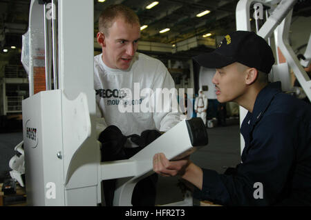 060224-N-1332Y-046 Yokosuka, Japan (Feb. 24, 2006) Ð The conventionally-powered aircraft carrier USS Kitty HawkÕs (CV 63) Morale Welfare and Recreation (MWR) fitness coordinator, Chad Quinn, works with a Sailor in the hangar bay to assemble and test new gym equipment. MWR is installing new equipment in the several workout facilities aboard the Kitty Hawk while the ship is in port. Kitty Hawk demonstrates power projection and sea control as the U.S. Navy's only forward-deployed aircraft carrier. U.S. Navy photo by Photographer's Mate Airman Adam York (RELEASED) US Navy 060224-N-1332Y-046 Morale Stock Photo