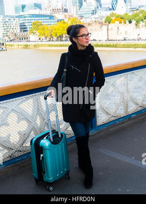 Young woman with suitcase standing on a bridge, Thames, London, England, United Kingdom Stock Photo