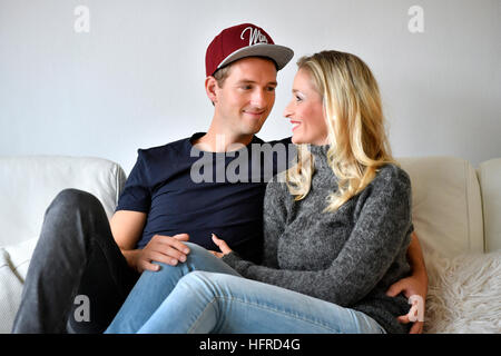 Young couple, lovers sitting on sofa, looking at each other Stock Photo