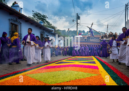 Antigua, Guatemala - April 16, 2014: Man wearing purple and white robes, carrying a float (anda) during the Easter celebrations. Stock Photo