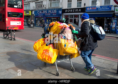 Hackney. Kingsland Road. Homeless person with a shopping trolley of possessions, most in Sainsburys bags Stock Photo