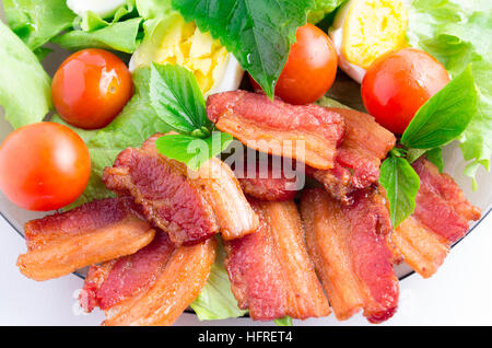 Top view of a fragment of a plate closeup with shredded lettuce, cherry tomatoes, bacon, herbs and boiled eggs with shallow depth of focus Stock Photo