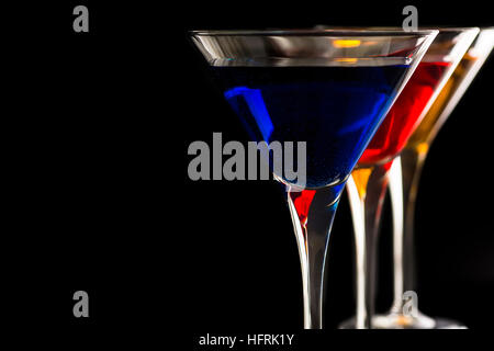 Colorful Cocktails in Martini Glasses on Black Background. Bar Commercials Concept. Stock Photo