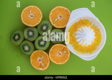 Up view of oranges and kiwis catted on half on green surface Stock Photo