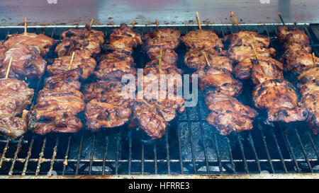 BBQ chicken lined up on a large outdoor grill with smoke coming up from the fire below. Stock Photo