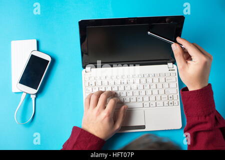 Man using a white lap top on blue table Stock Photo