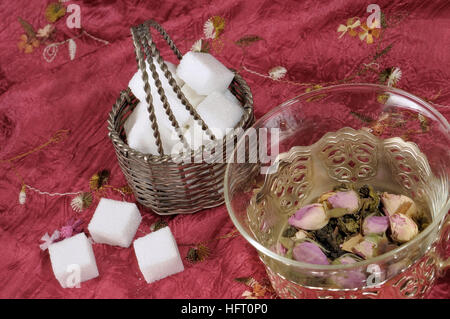 Exotic fruit and flower tea and cubes of sugar on red table cloth close-up image Stock Photo