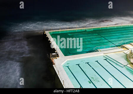 Fragment of public municipal rock pool at Bondi beach in Sydney earlier in the morning. Brightly illuminated lanes of sports facility. Stock Photo