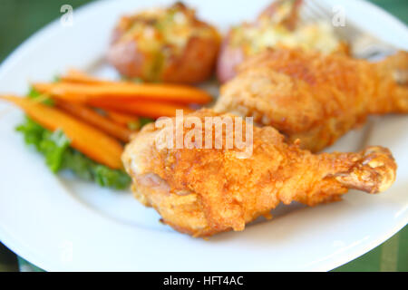 Closeup of fried chicken legs with roasted carrots and crushed potatoes Stock Photo