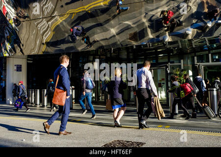 Passengers enter and exit the entrance to Birmingham New Street Railway Station. The modern materials reflect the people from above Stock Photo