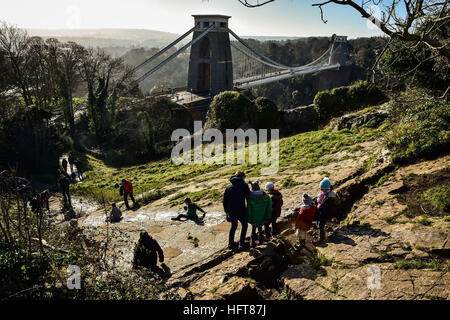 Children slide down a natural rock slide, which has been created by generations of children sliding down the limestone slope near Clifton Suspension Bridge on Clifton Downs, Bristol, as parts of the UK will be gripped by icy conditions as a cold snap kicks off 2017. Stock Photo