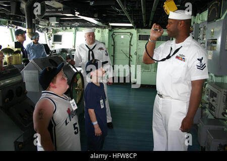 050613-N-8110K-017 Boston, Mass. (June 13, 2005) – Boatswain’s Mate 1st Class Dwayne Lawson demonstrates the bos’n whistle to children from the Spaulding Rehabilitation Hospital, aboard USS Shreveport (LPD 12). The boys were invited to tour the ship as part of the Navy Office of Community Outreach (NAVCO), “Caps for Kids” program. Shreveport’s visit and the “Caps for Kids” program are just two of the many events scheduled during Boston Navy Week. Twenty such weeks are planned this year in cities throughout the U.S., arranged by the Navy Office of Community Outreach. NAVCO is a new unit tasked  Stock Photo