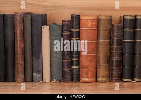 Old books on a wooden shelf. No labels, blank spine. Stock Photo