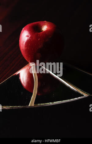 Red apple on cracked broken mirror reflecting Stock Photo