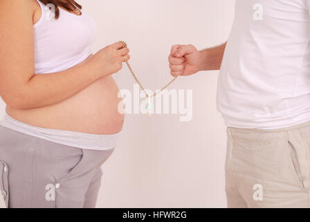 Pregnant woman and her husband in his hands Dummies on grey background Stock Photo