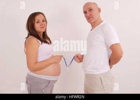 Pregnant woman and her husband in his hands Dummies on grey background Stock Photo
