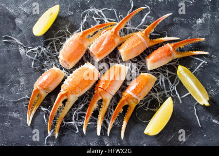 Cooked crab claws with lemon, sea salt and pepper on a concrete background - concept of healthy eating, dieting and cooking. Top view. Stock Photo