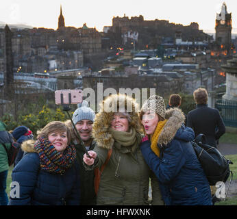 Tourists take a selfie on Calton hill with the Edinburgh skyline and Edinburgh Castle in the distance. Stock Photo