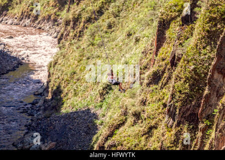 Young Man Hanging On A Rope After The Bungee Jump Against The Pastaza River, Banos De Agua Santa, Ecuador, South America Stock Photo