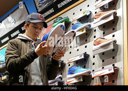 Coquitlam, BC, Canada - December 30, 2016 : Young man comparing two pair of exposition sport shoes in Coquitlam BC Canada. Stock Photo