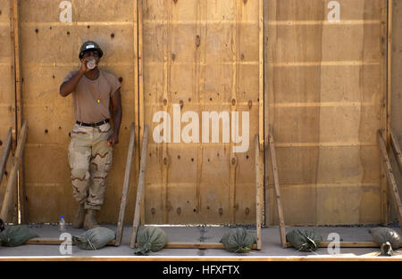 While resting in the shade, Petty Officer 3rd Class Terence Ruben, Naval Mobile Construction Battalion 3, takes a drink of juice, Camp Lemonier, Djibouti, Nov. 8, 2005. The two new buildings will be used to combine and house the Joint Task Force-Horn of Africa's Future Operations personnel, who are currently separated in different work tents. (RELEASED) (U.S. Air Force photo by Staff Sgt. Stacy L. Pearsall) US Navy 051108-F-7234P-068 While taking a break in the shade, U.S. Navy Petty Officer 3rd Class Terence Ruben, assigned to Naval Mobile Construction Battalion Three (NMCB-3), takes a drink  Stock Photo