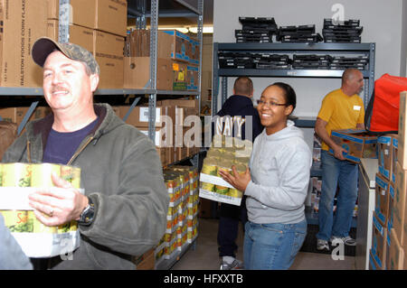 091123-N-1580K-944 BRUNSWICK, Maine (Nov. 23, 2009) Chief Builder Dan Meddison, left, Logistics Specialist 2nd Class Gloria Pearson and Sailors assigned to Naval Air Station (NAS) Brunswick carry boxes of canned vegetables while at the Mid Coast Hunger Prevention Program (MCHPP) storehouse. NAS Sailors are teaming with MCHPP in a community relations project to collect and help sort meats, produce, breads and pastries donated to local supermarkets so the citizens of Brunswick can have Thanksgiving dinner. (U.S. Navy photo by Mass Communication Specialist 2nd Class Ron Kuzlik/Released) US Navy 0 Stock Photo