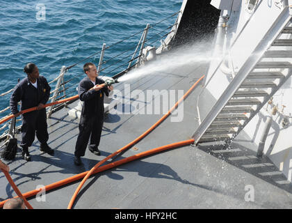 Erin Lagos, damage control fireman, sprays down part of the Arleigh Burke-class guided-missile destroyer USS Farragut, while Petty Officer 1st Class Tara Johnson, electrician's mate, steadies the hose during a fresh water wash down of the ship. The Farragut is part of Combined Task Force 151, a multinational task force established to conduct anti-piracy operations in the Gulf of Aden. Vertical replenishment at sea DVIDS253532 Stock Photo