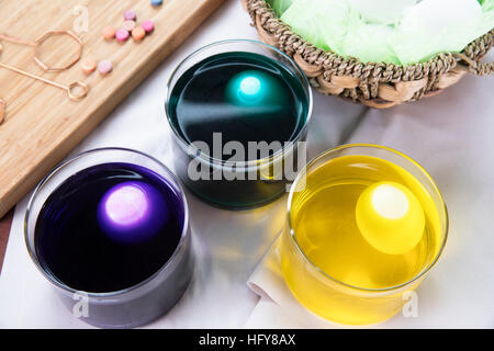 Three eggs in cups of dye for Easter Stock Photo