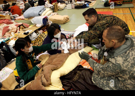 110321-M-2739S-007 AICHI, Japan (March 21, 2011) Lt. Cmdr. Ewell Hollis, a physician assigned to III Marine Expeditionary Force, examines a Japanese woman who broke her arm during the tsunami at an emergency shelter established at a school. U.S. armed forces and Japan Ground Self-Defense Forces are surveying the school for plans to establish power, food and water supply lines in support of Operation Tomodachi after a 9.0 earthquake and subsequent tsunami struck Japan March 11. (U.S. Marine Corps photo by Gunnery Sgt. Leo Salinas/Released) US Navy 110321-M-2739S-007 Lt. Cmdr. Ewell Hollis, a ph Stock Photo