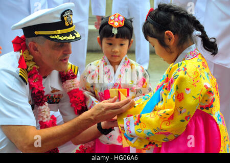 Capt. David Lausman, commanding officer of the aircraft carrier USS George Washington (CVN 73), presents a command coin to a Korean girl after arriving in Busan, Republic of Korea, for a port visit. George Washington pulled out of her forward operating port of Yokosuka, Japan, Sept. 19 to continue her 2011 patrol. (Photo by: Seaman Kaitlyn R. Breitkreutz) USS George Washington activity 110919-N-QQ884-029 Stock Photo