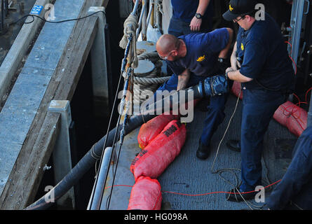 Civilian mariners pull a fuel hose aboard the decommissioned Spruance-class destroyer self defense test ship USS Paul F. Foster that is moored at the fuel pier at Naval Base Point Loma. Foster, homeported at Port Hueneme, arrived at Point Loma to receive 20 thousand gallons of a biofuel diesel mixture, the largest amount to ever be used in a United States ship. This event is one of many to come as part of the Secretary of the Navy Ray Mabus’ plan toward a more energy efficient Navy and the sailing of “The Great Green Fleet” by 2012. USS Paul F. Foster in Point Loma 111116-N-ZS026-099 Stock Photo