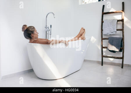Young woman relaxing in bathtub. Caucasian female lying in bathtub. Stock Photo