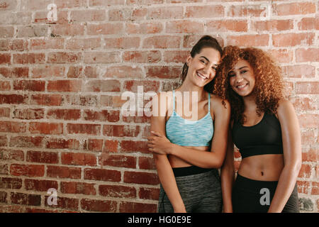 Three fitness young girls in sportswear standing against wall in fitness  gym. Girls smiling and looking to the camera Stock Photo - Alamy