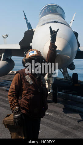 A plane captain signals to directors that an F/A-18C Hornet assigned to the 'Golden Dragons' of Strike Fighter Squadron (VFA) 192 is ready to be moved on the flight deck of aircraft carrier USS John C. Stennis (CVN 74). John C. Stennis is deployed to the 5th Fleet area of responsibility conducting maritime security operations, theater security cooperation efforts and support missions for Operation Enduring Freedom. (U.S. Navy photo by Mass Communication Specialist 3rd Class Kenneth Abbate/Released) USS John C. Stennis 121025-N-OY799-379 Stock Photo