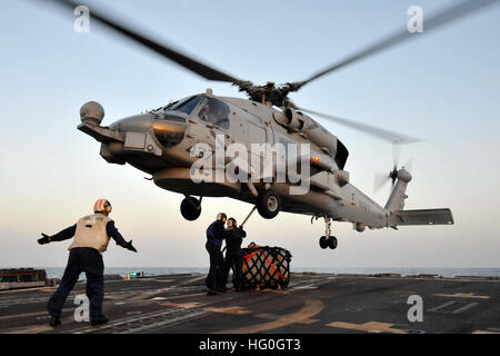 130222-N-XQ375-207  U.S. 5TH FLEET AREA OF RESPONSIBILITY (Feb. 22, 2013) Boatswain's Mate 3rd Class Nick Kotoun, right, and Boatswain's Mate 3rd Class Julius McGowan, center, hook a cargo net to an SH-60B Sea Hawk helicopter assigned to the Proud Warriors of Helicopter Anti-Submarine Squadron Light (HSL) 42, Det. 7, as Boatswain's Mate 1st Class Archie Folks signals during a vertical replenishment exercise aboard the guided-missile destroyer USS Jason Dunham (DDG 109). Jason Dunham is deployed with the John C. Stennis Carrier Strike Group to the U.S. 5th Fleet area of responsibility conductin Stock Photo