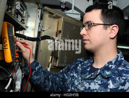 An Electronics Technician measures voltage on a common data link management system in the self-defense computer room aboard aircraft carrier USS Nimitz (CVN 68) in Everett, Washington, during maintenance operations. Stock Photo