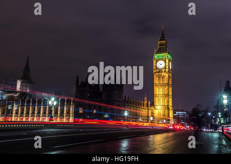 The Houses of Parliament's Christmas tree as seen from behind the Winston Churchill Statue of Parliament Square and the lights from cars and buses streak past the Queen Elizabeth II Tower which contains the bell known as Big Ben during long exposure photo Stock Photo