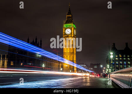 The Houses of Parliament's Christmas tree as seen from behind the Winston Churchill Statue of Parliament Square and the lights from cars and buses streak past the Queen Elizabeth II Tower which contains the bell known as Big Ben during long exposure photo Stock Photo