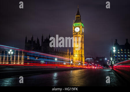 The Houses of Parliament's Christmas tree as seen from behind the Winston Churchill Statue of Parliament Square and the lights from cars and buses streak past the Queen Elizabeth II Tower which contains the bell known as Big Ben during long exposure photo Stock Photo