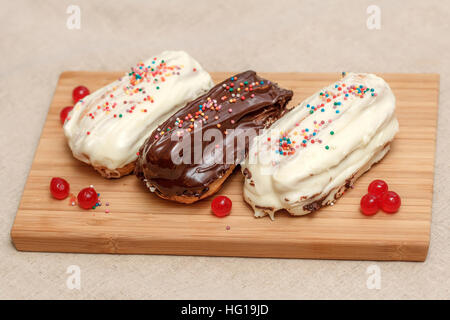 Eclair cakes with white and brown cream on wooden board Stock Photo
