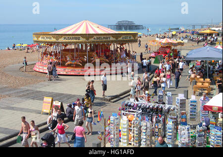 People on Brighton seafront, postcards. people, carousel, cafe and the remains of Old west pier, view from the promenade above. Stock Photo