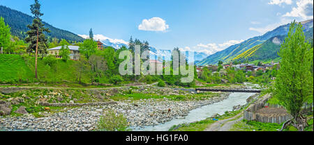 The rocky banks of Mestiachala river with the houses of Mestia and huge mountain ranges on the background, Upper Svaneti, Georgia.
