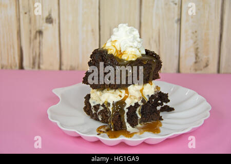 chocolate brownie sundae with dripping caramel sauce on white seashell plate Stock Photo