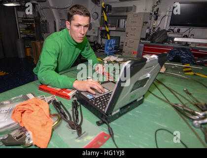 Aviation Structural Mechanic aboard amphibious assault ship USS Makin Island (LHD 8) performs step-by-step aircraft maintenance, using technical manuals and laptop guidance during composite training exercises in preparation for scheduled deployment. Stock Photo