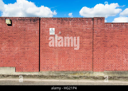 Red brick wall with a warning sign of high voltage danger Stock Photo