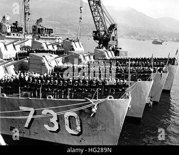 Photo #: NH 97090  Teamwork, Courage, and Skill  Men of Destroyer Division 91 crowd the foc'sle and superstructure of their ships in Sasebo, Japan, to receive their Navy Unit Commendations. During the presentation on the Mansfield, a crane crew in the background continues its task of installing new gun barrels on the De Haven. Streaks of red lead on the Collett and the Swenson in the foreground show the work that has occupied all the crews while in port. By coincidence the famed 'Sitting Duck' destroyers are berthed in their numerical order: USS De Haven (DD-727), Mansfield (DD-728), Lyman K.  Stock Photo